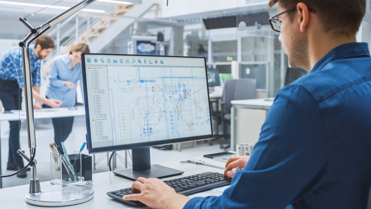Dynamo electrical engineer in front of a computer. The location is in an office setting. The employee is working on a CAD program.